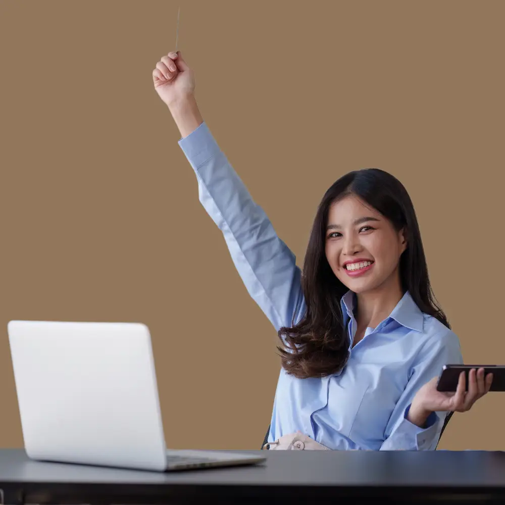 a woman showing excitement by raising on hand in the air looking at a laptop computer happy she is saving money for her business with online reputation management software