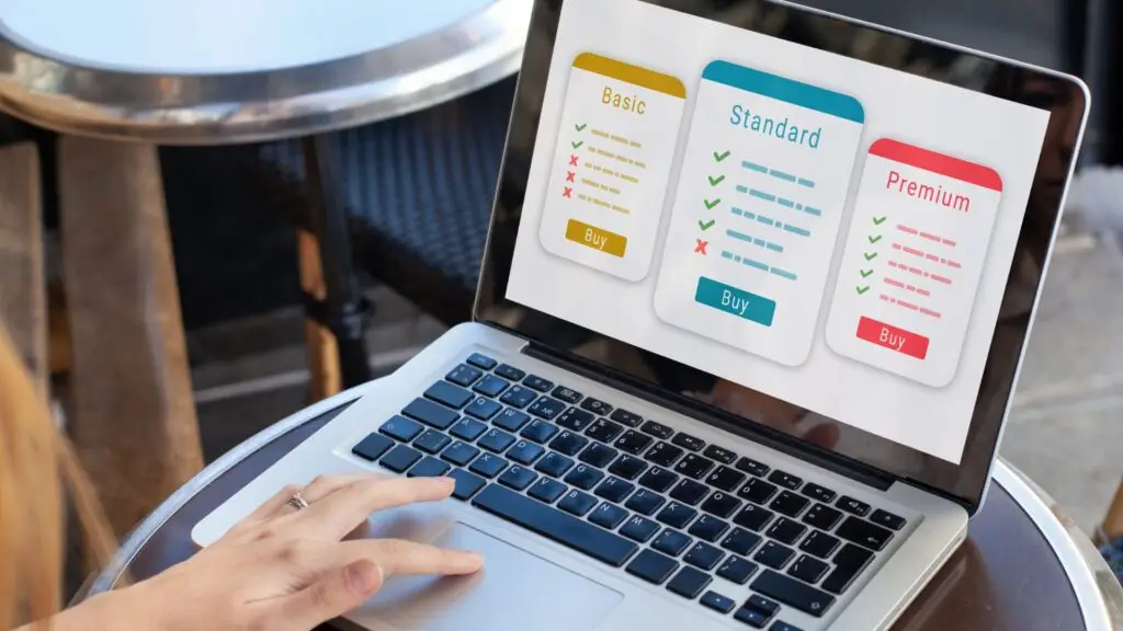 image of a laptop with what seems to be reputation management software being displayed. There is one visible hand with a finger touching the trackpad seemingly navigating the pricing tiers for the review management software.