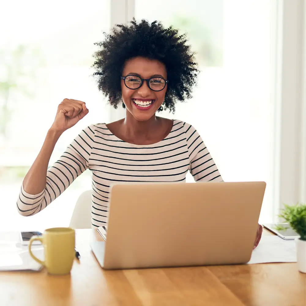 Alt Text: African American professional woman with afro managing online reputation at desk with computer, specializing in review management.